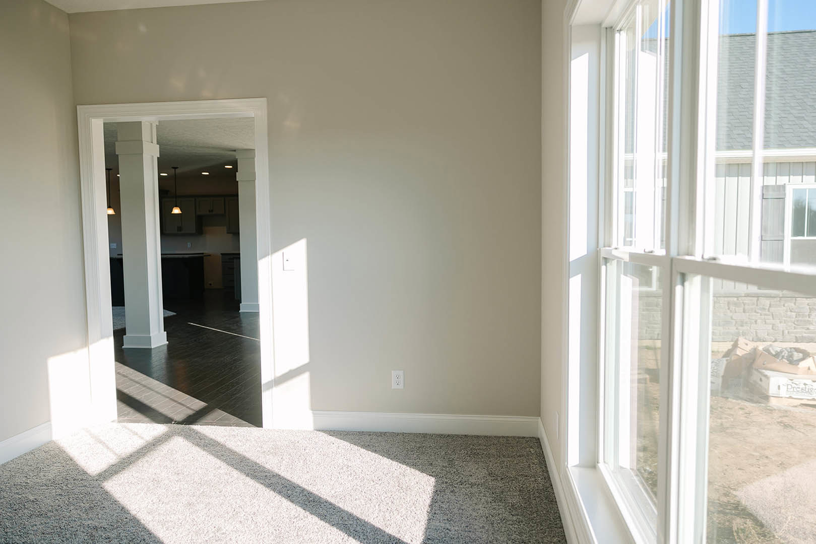 Spacious room featuring a large window with daylight, glossy tile flooring, neutral walls, and partial view of adjacent building exterior.