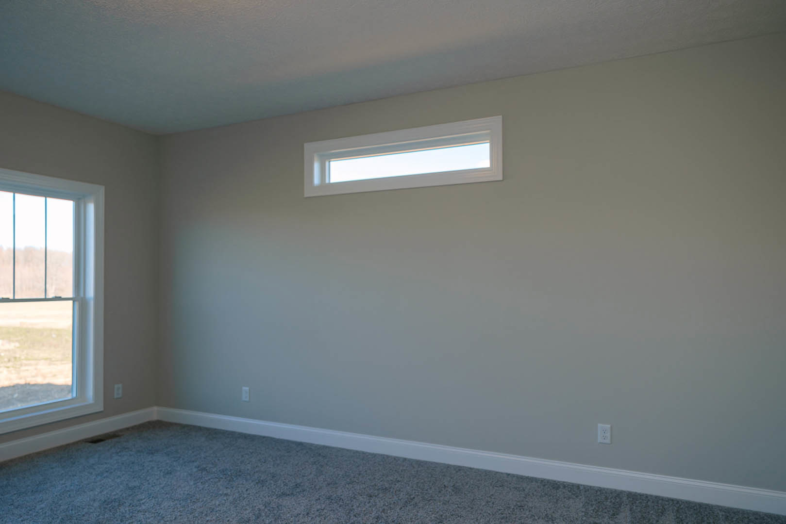 Rectangular window with white trim set in a white wall, plush beige carpet flooring, white ceiling, and soft natural daylight illuminating the room