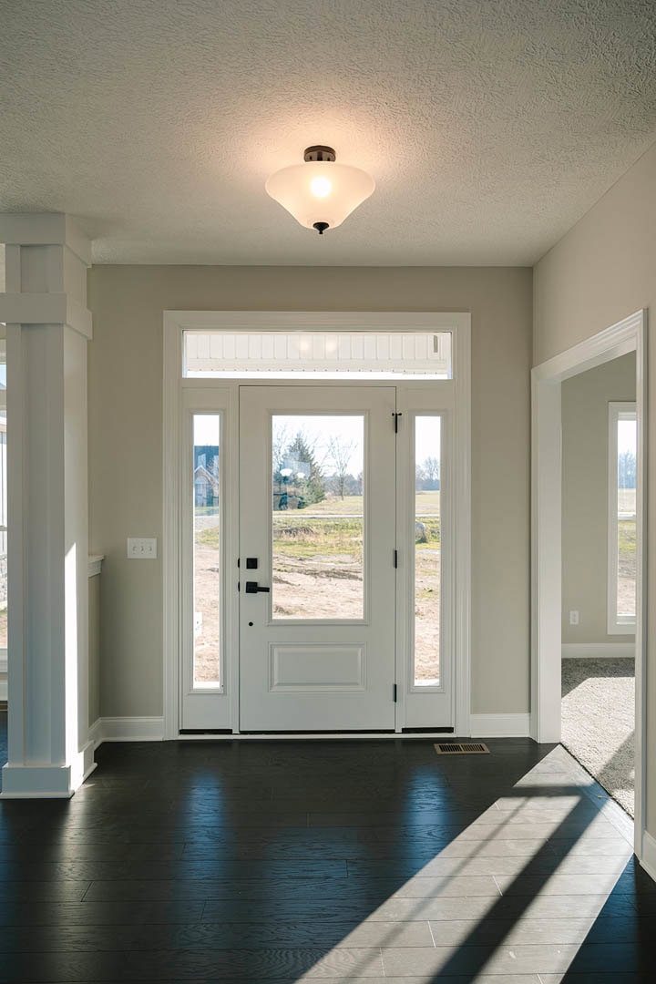 White door with glass panels, dark hardwood floor with floor vent, white walls, ceiling light fixture, sunlight streaming through window