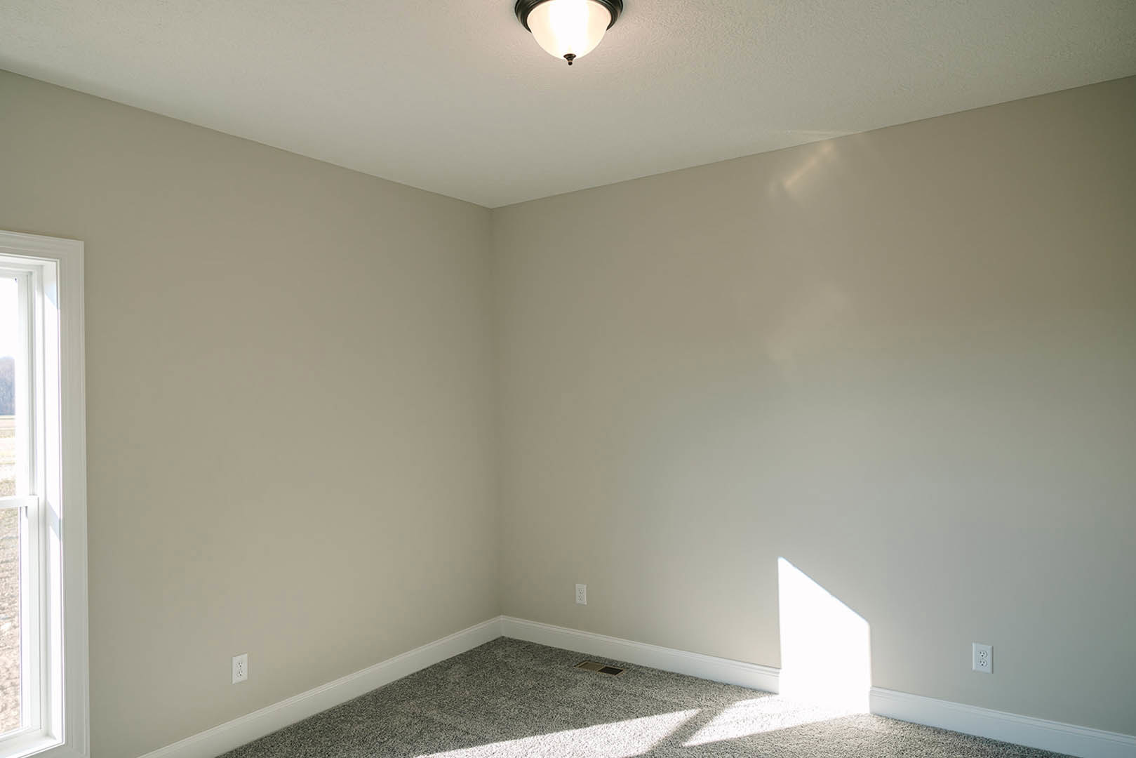 White ceiling with recessed light fixture, white door with panel molding, smooth plaster walls, and floor vent in a residential interior.