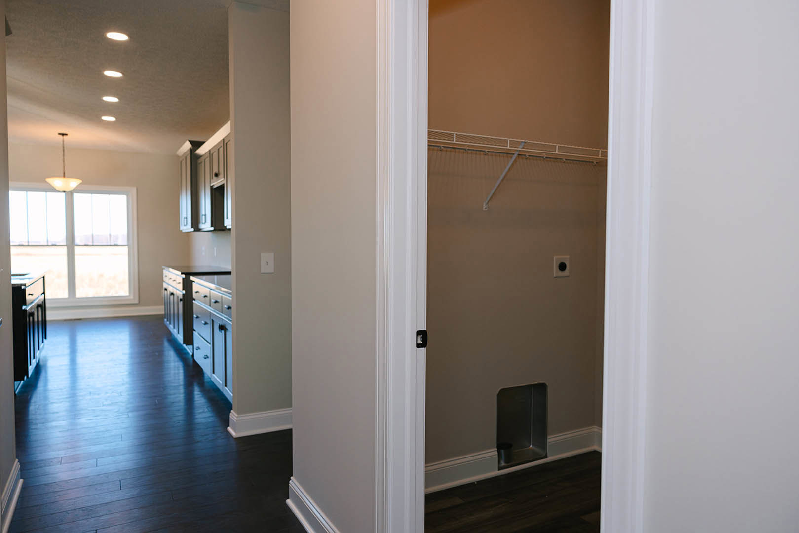 Walk-in closet with dark hardwood floor, white trim, built-in dresser, window, and neutral walls