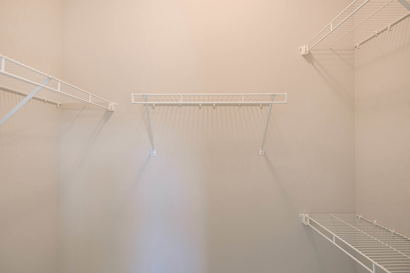 White wire shelving mounted on a plaster wall in an indoor space with minimal decor.