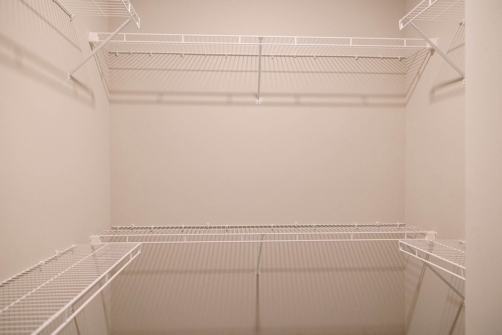 Walk-in closet with built-in white shelving, hanging rods, and hooks against plaster walls