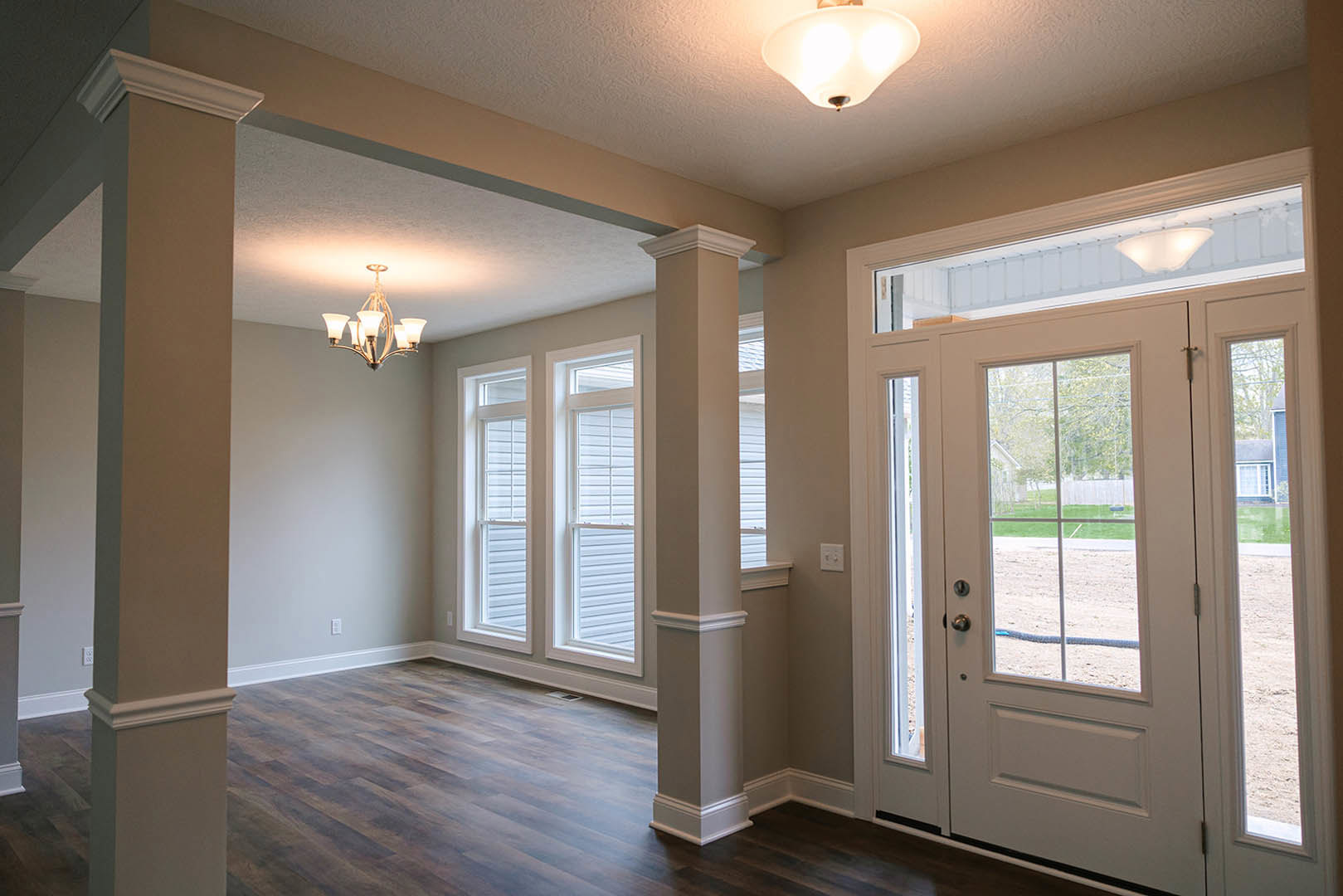 Hallway with white paneled door and adjacent glass door, light fixture mounted on ceiling, wood flooring, white walls with crown molding