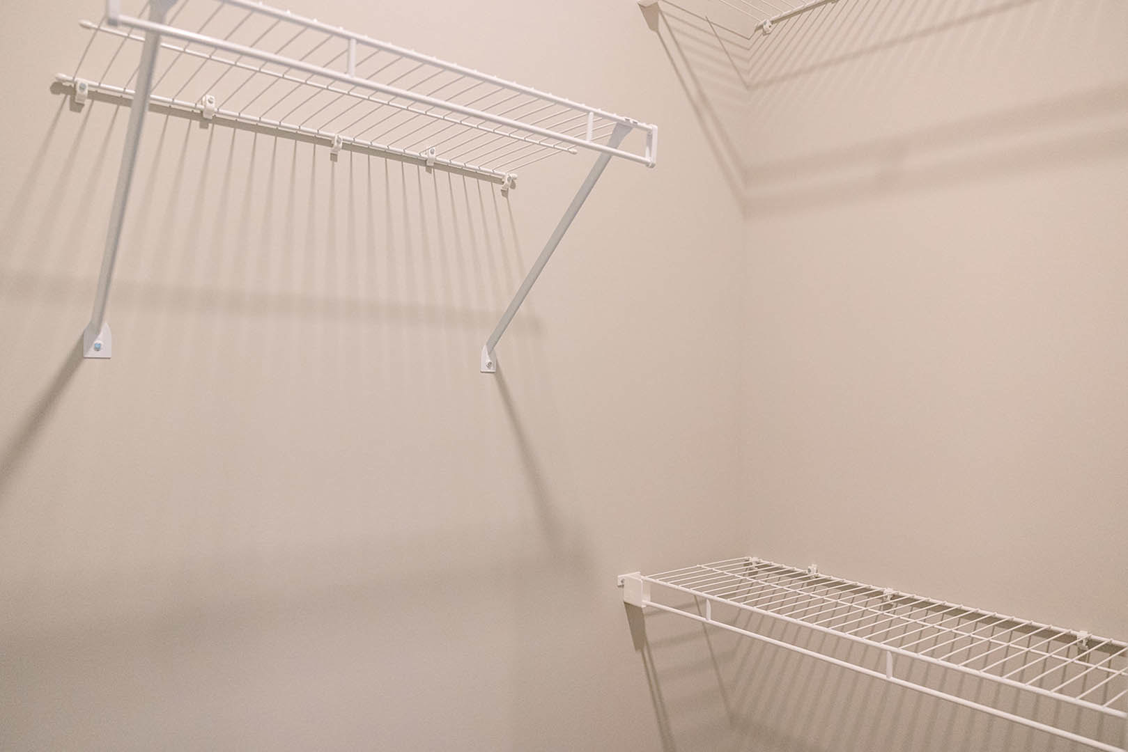 White wire shelving unit with built-in hooks mounted on a white wall in a room.