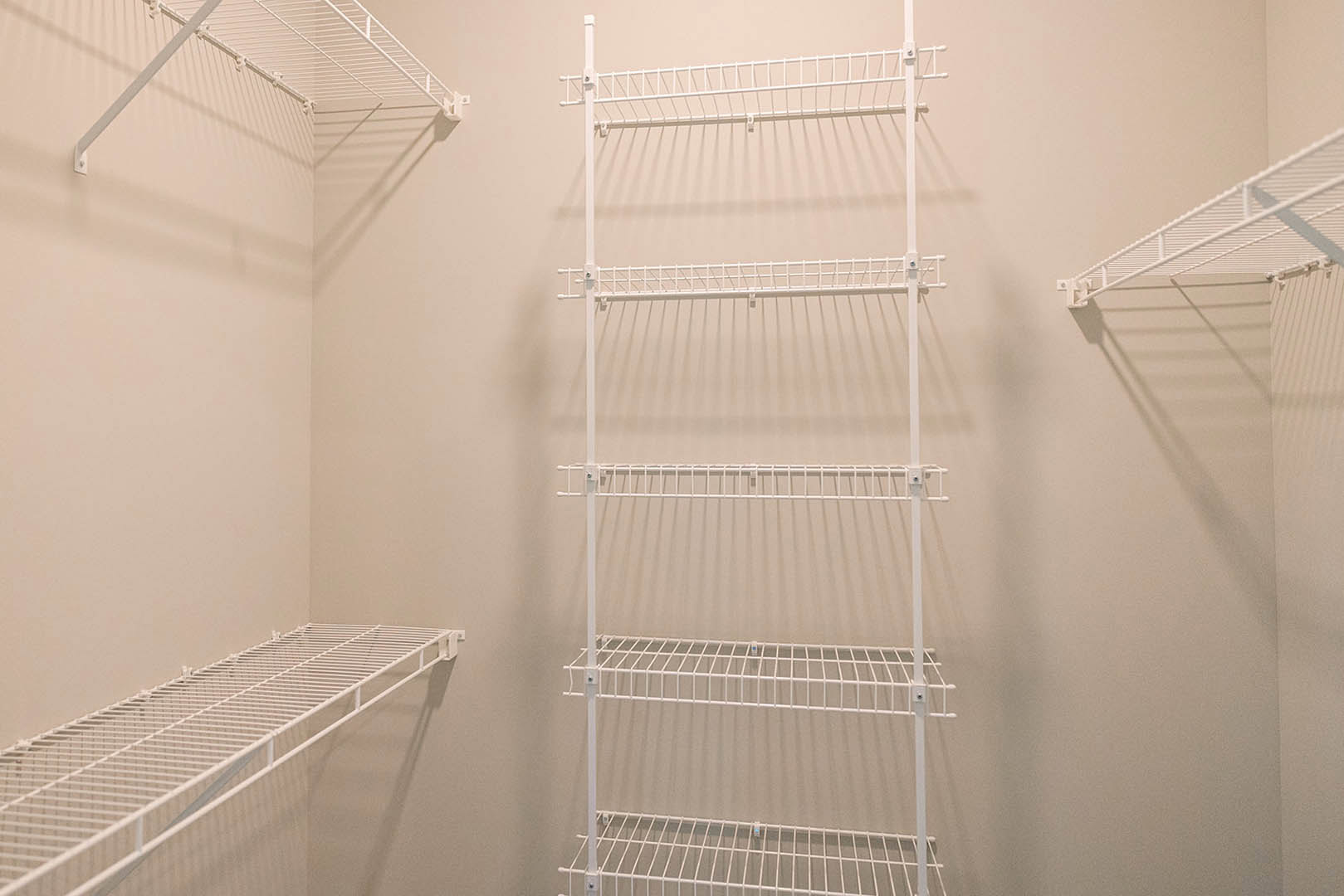 White wire shelf mounted on a white wall in a room, featuring perforated metal design and minimalist finishes.