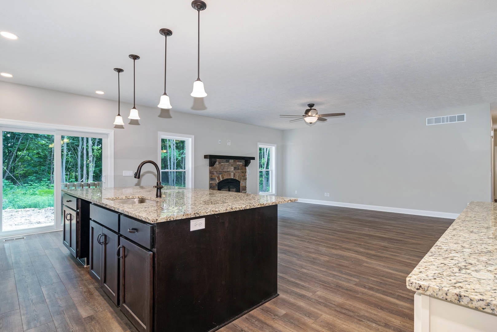 Marble kitchen island with built-in sink, central fireplace surrounded by cabinetry, white outlet with black border, sliding glass door, light flooring, and modern finishes