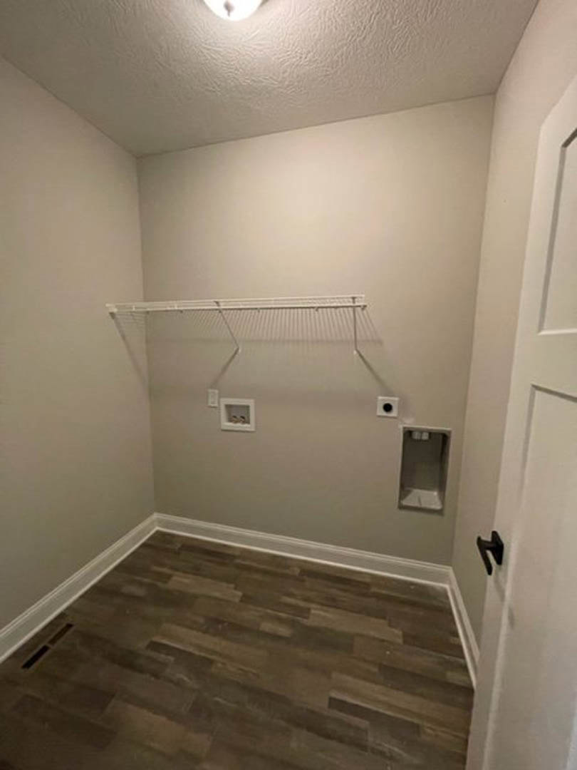 Bathroom with wood flooring, white wall rack, white trim, and plaster walls