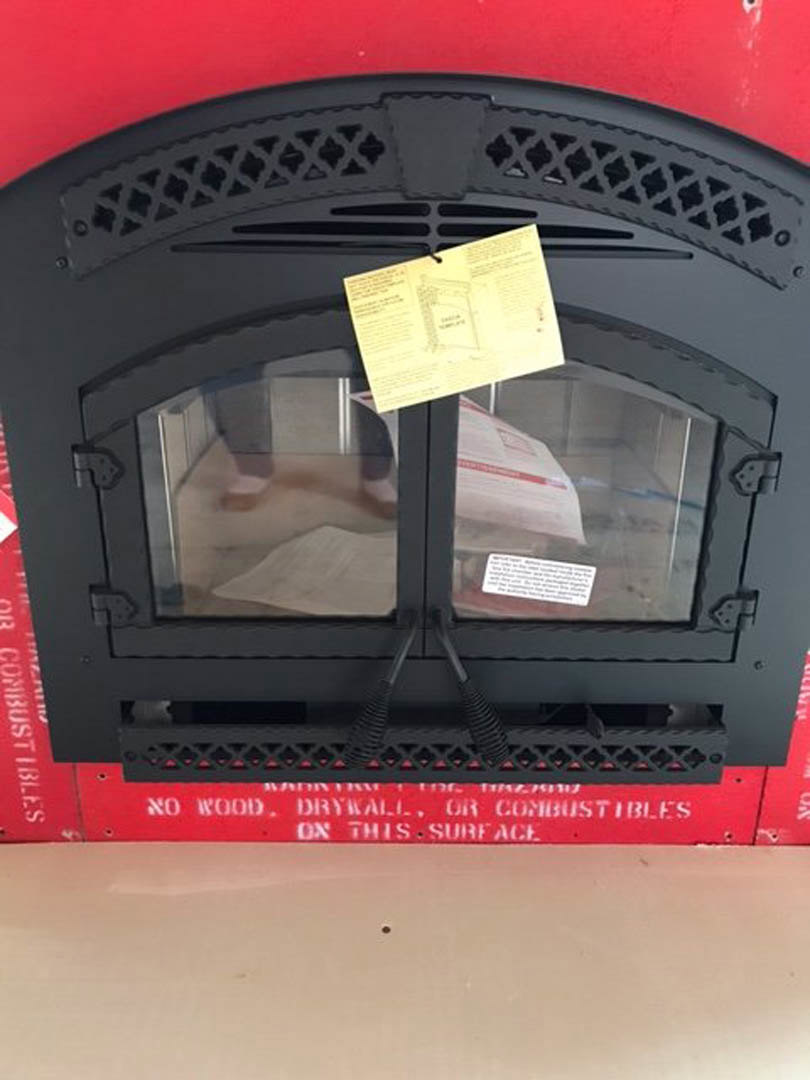 Black and red fireplace in a modern living room, yellow paper taped to window, light walls, hardwood flooring