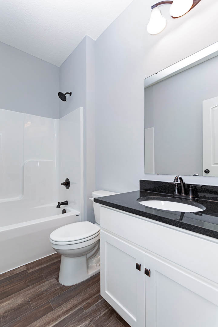 Modern bathroom featuring a white porcelain sink with chrome faucet, glass-enclosed shower with tiled walls, and a white toilet adjacent to a light-colored countertop.