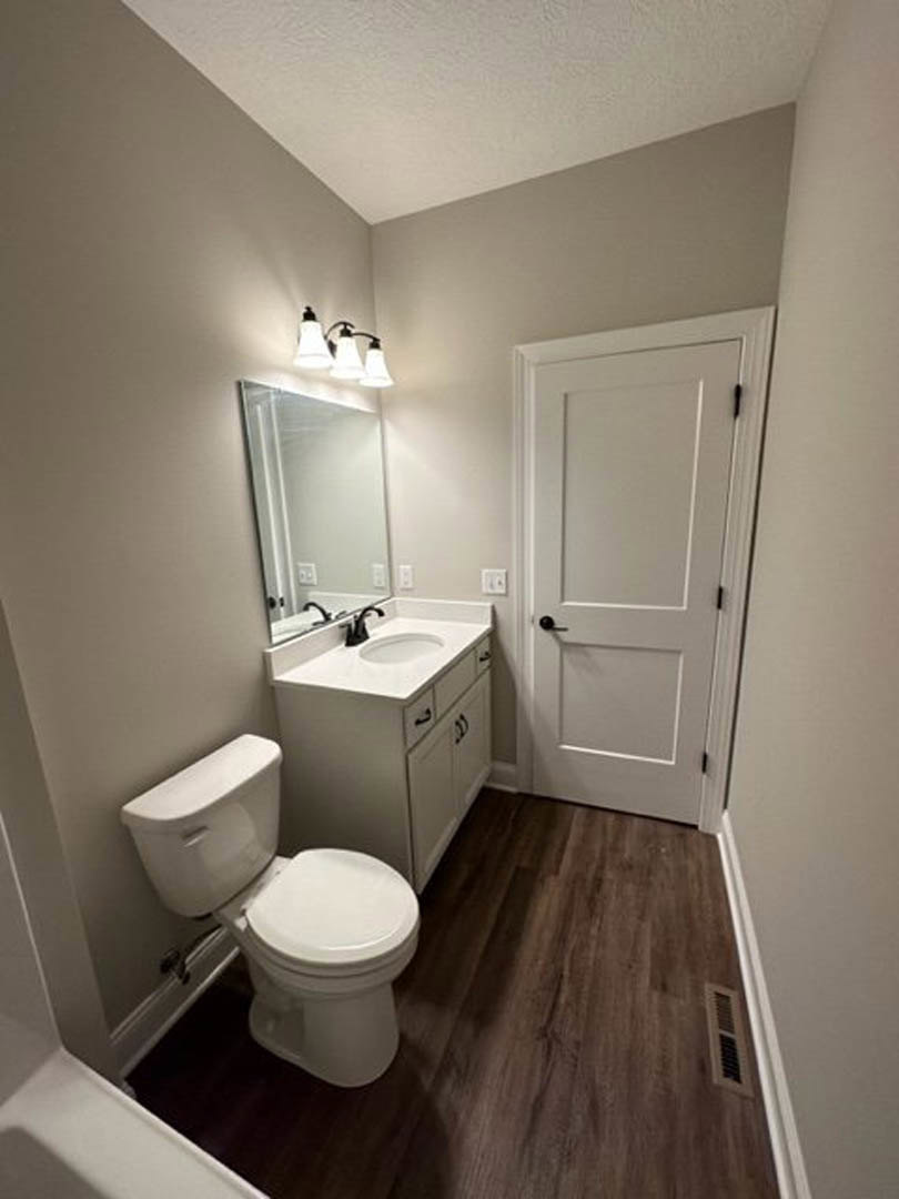 White toilet and rectangular sink with black faucet in a bathroom featuring light tile walls and floor.