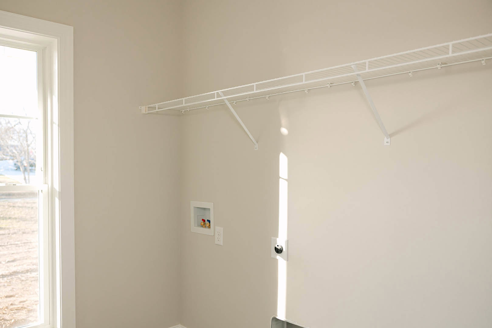 White floating shelf mounted on smooth white plaster wall, adjacent to window overlooking snowy landscape.