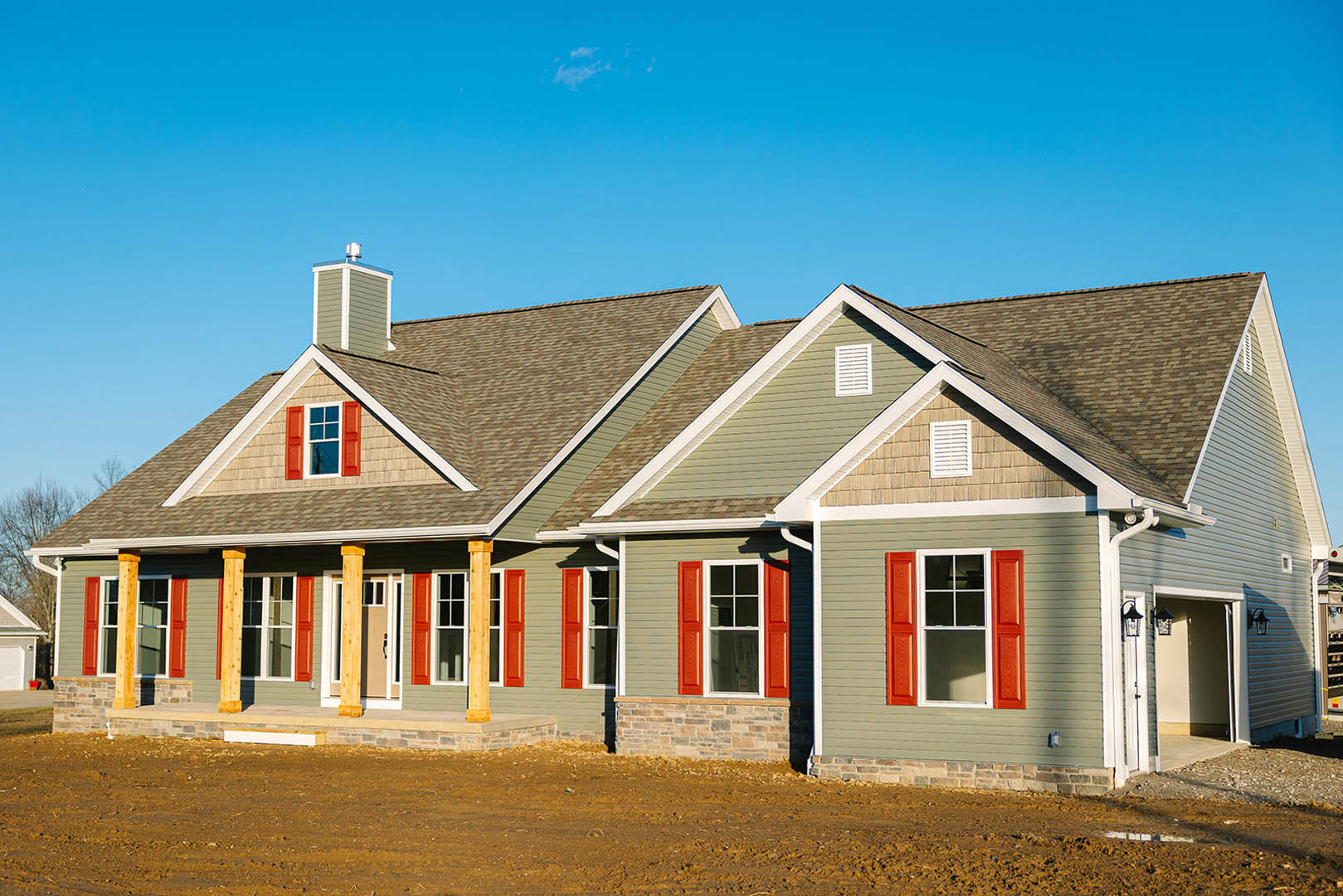 White siding house with brown accent wall, red shutters framing windows, white vent above window, gray shingle roof, blue sky background