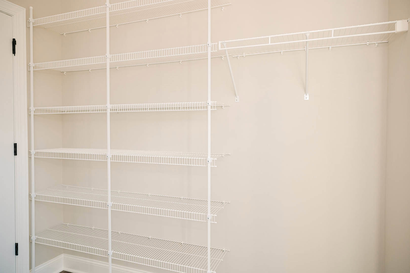White wire shelving mounted on a smooth white wall in a residential interior.