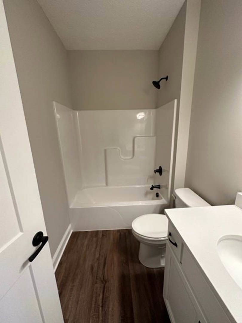 White bathroom with tile floor, modern toilet, rectangular sink on white countertop, chrome faucet, and neutral wall finishes