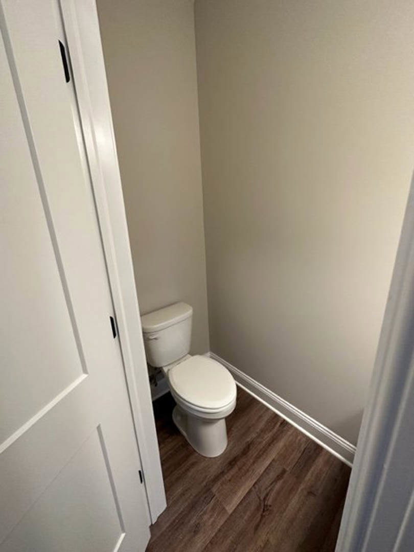 White toilet with closed lid in compact bathroom featuring light tile flooring and neutral wall tiles