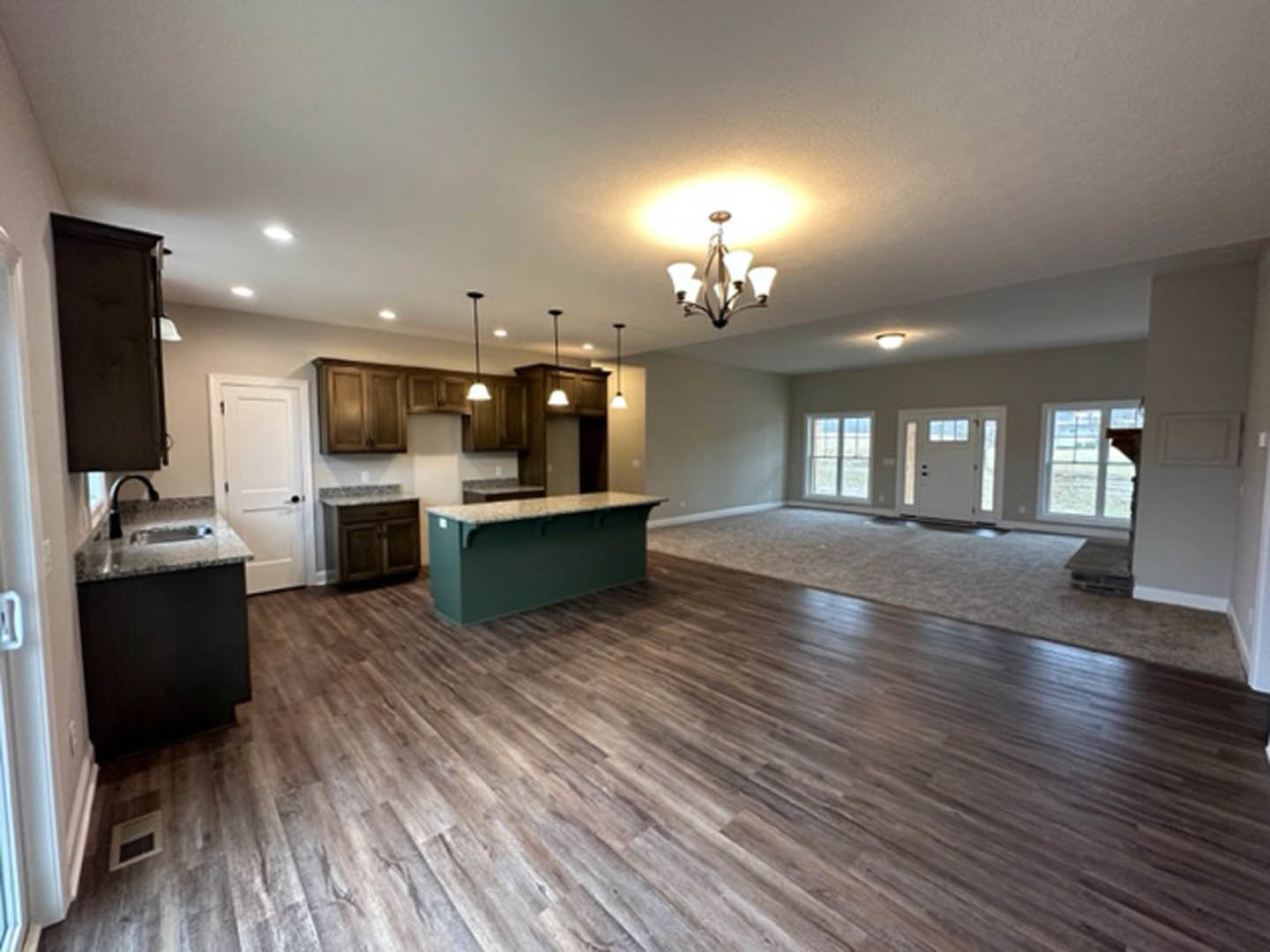 Spacious open concept kitchen with central island, hardwood flooring, white cabinetry, and glass-paneled door with black handle
