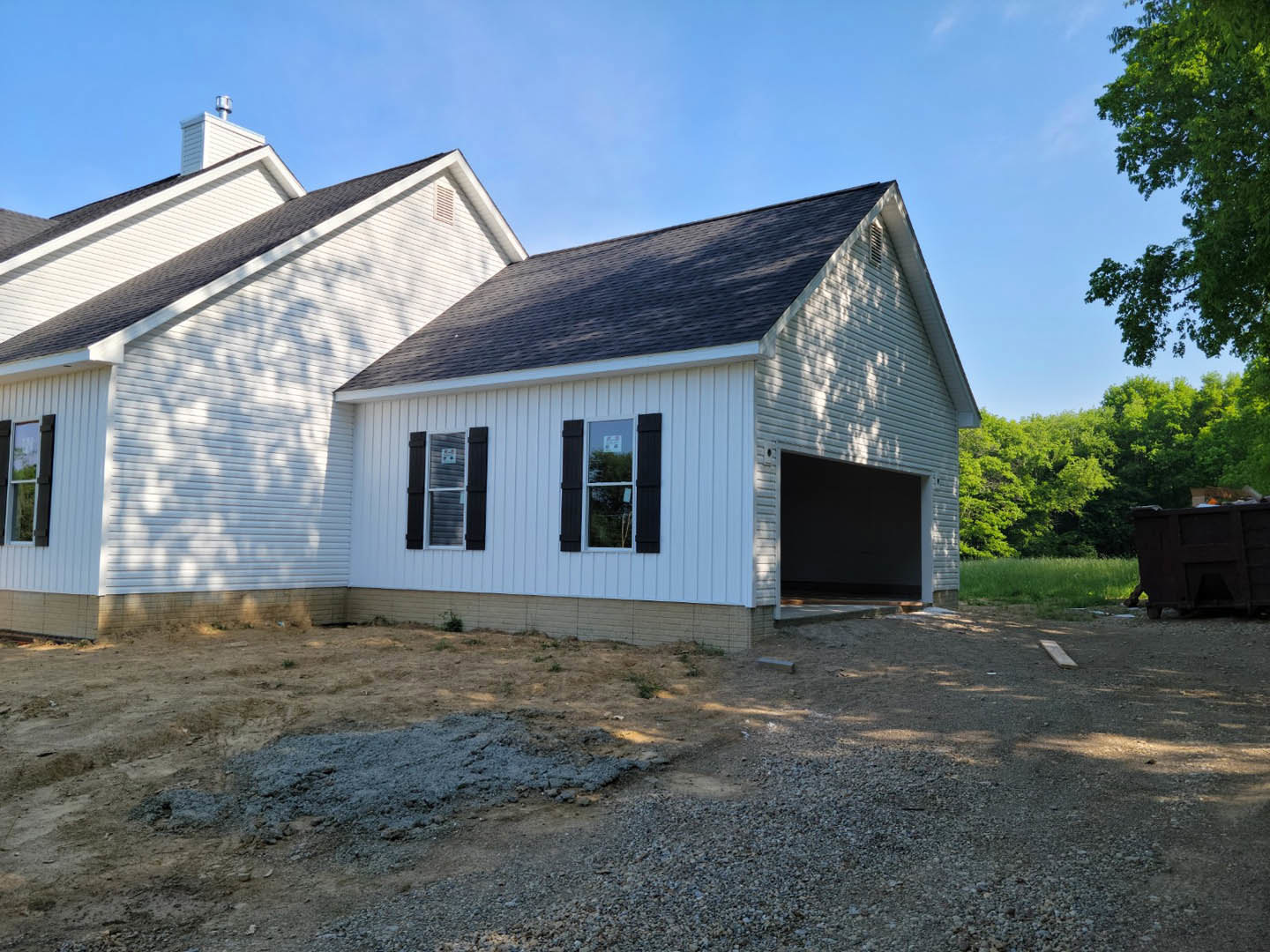 Two-story house with attached garage, white-framed windows, dark shutters, gray roof shingles, and landscaped front yard.
