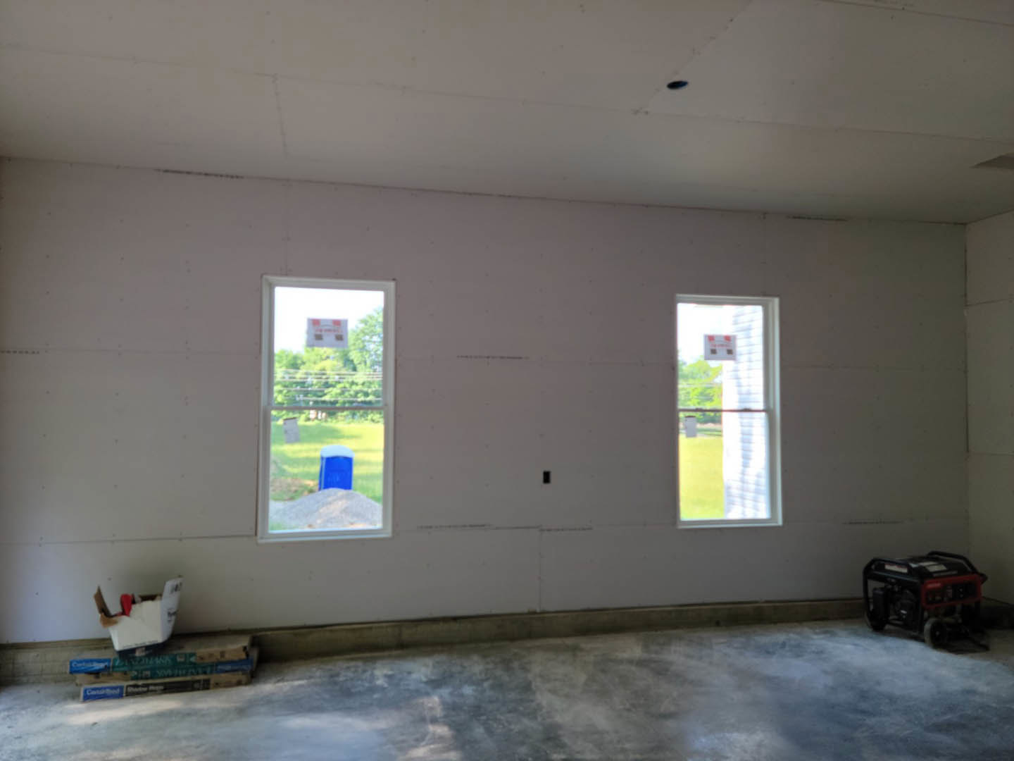 Bright room with two large windows, white plaster walls, light tile flooring, and minimal furnishings