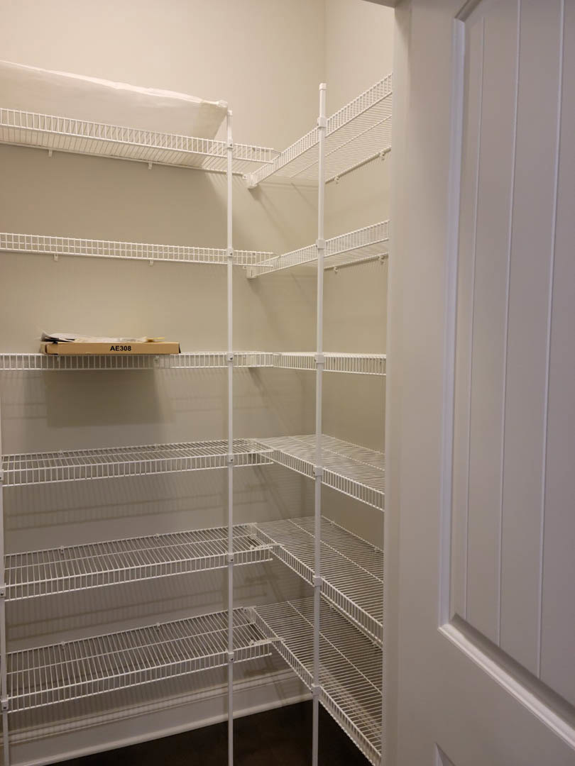 White built-in shelves inside an empty closet with white walls and door