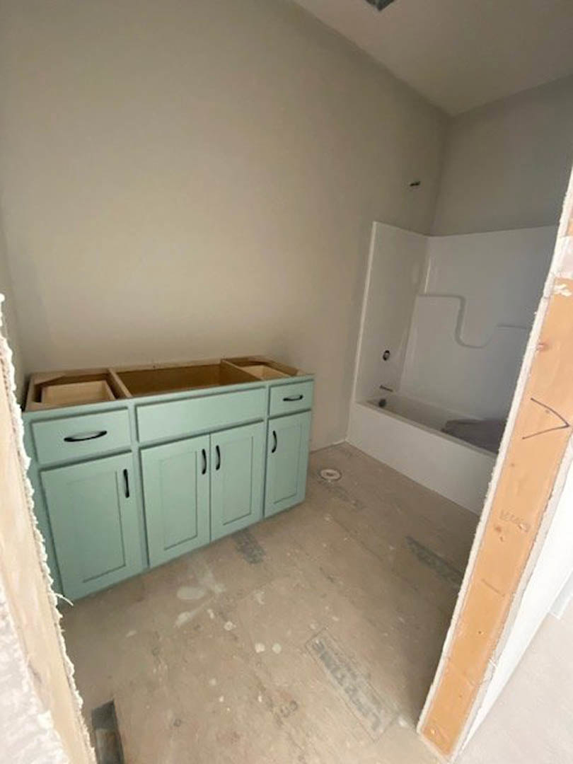 Bathroom with freestanding tub, white tile floor, wood cabinets with drawers, plaster walls, and chrome fixtures