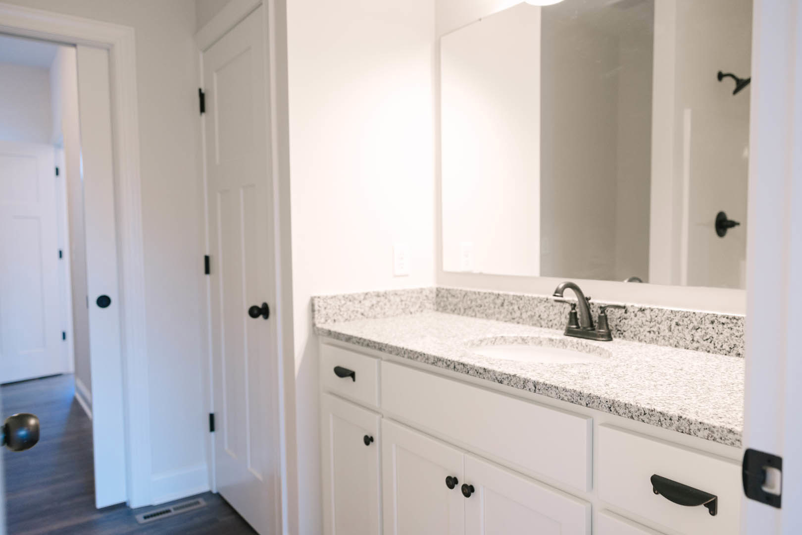 White tile bathroom with modern sink, chrome faucet, large mirror above vanity, and light wood cabinetry