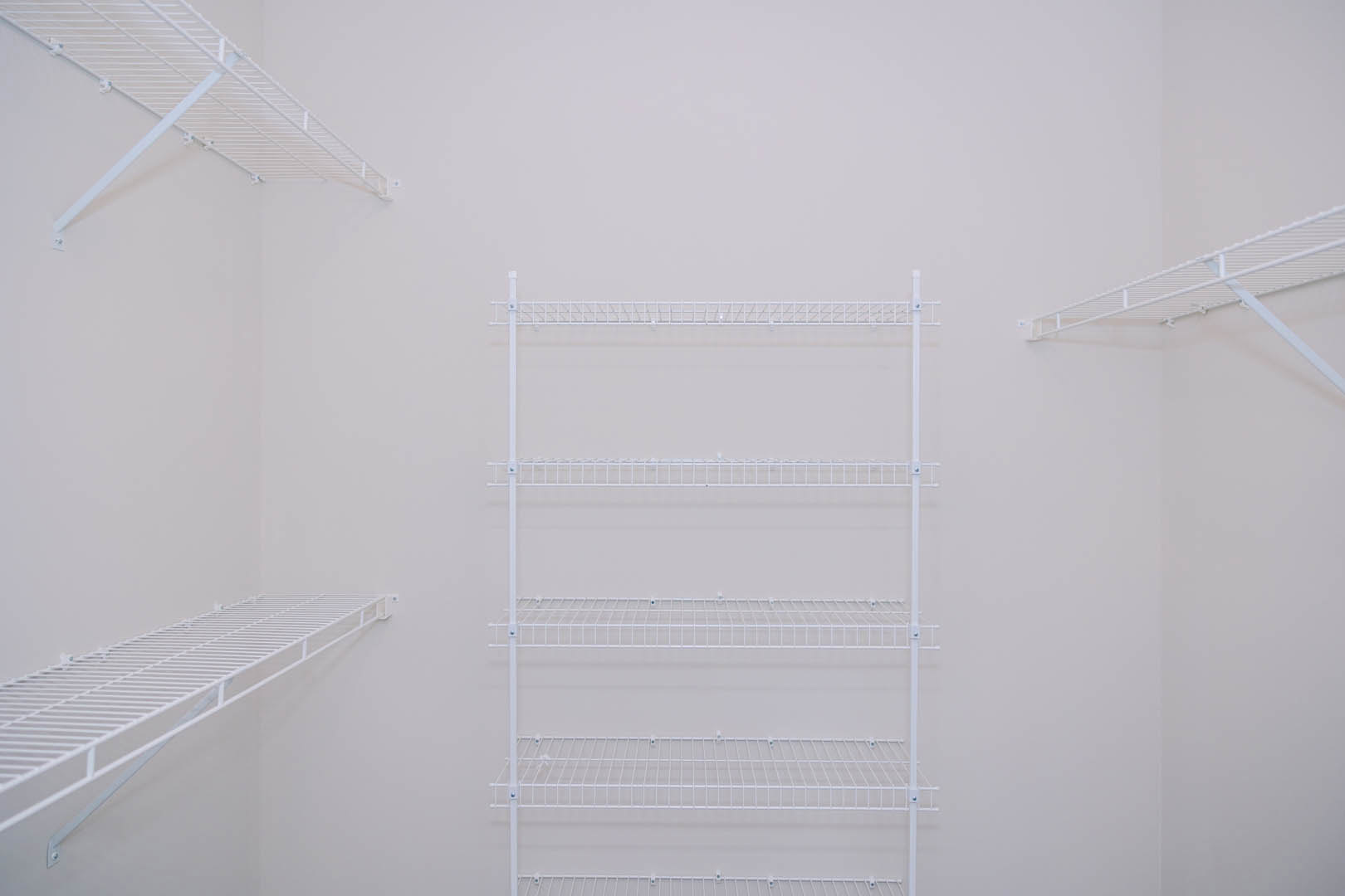 White wire shelving mounted on a white plaster wall in a minimalist room