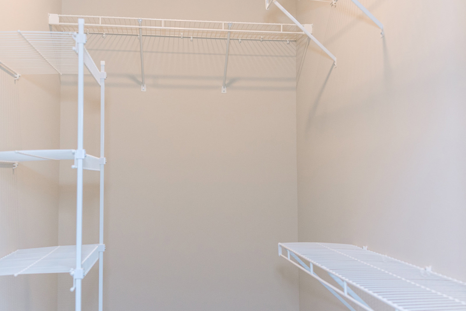 White metal shelving unit with horizontal bars mounted against a light-colored wall in a residential interior.
