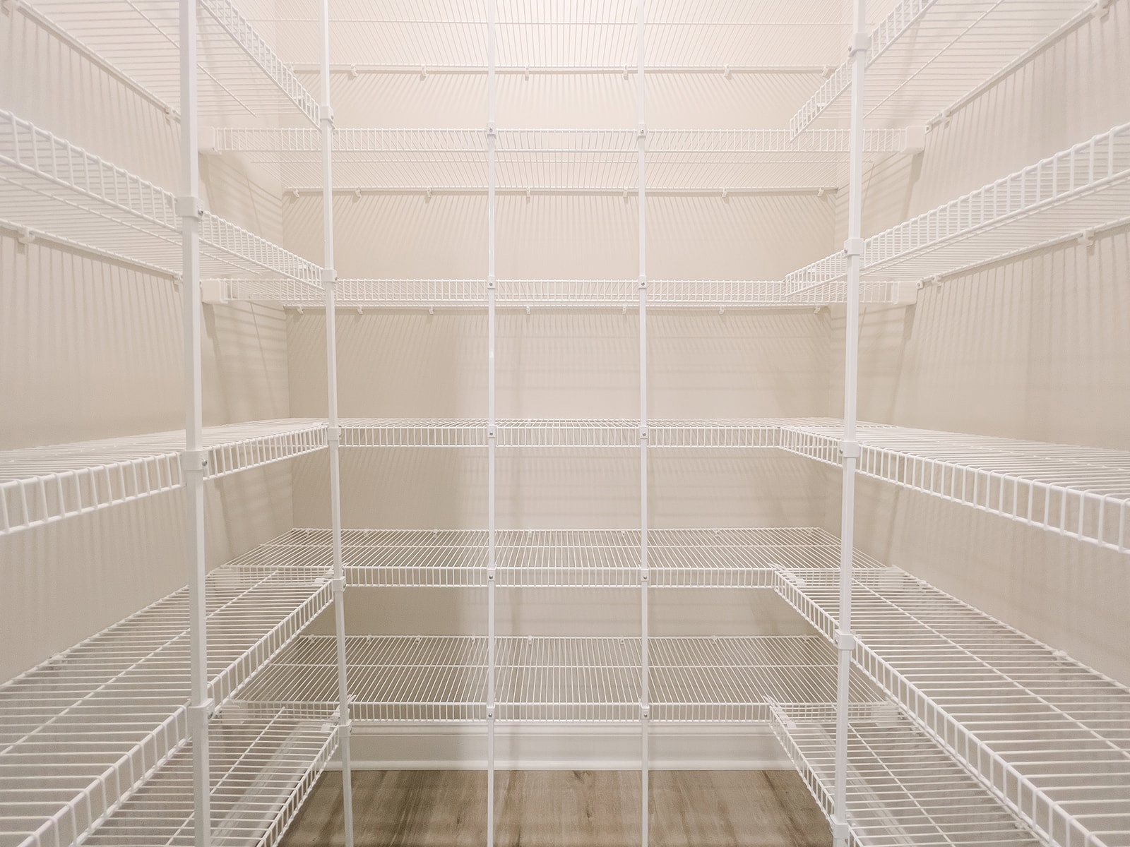Large empty white closet with white wire shelving along one wall and smooth painted surfaces.