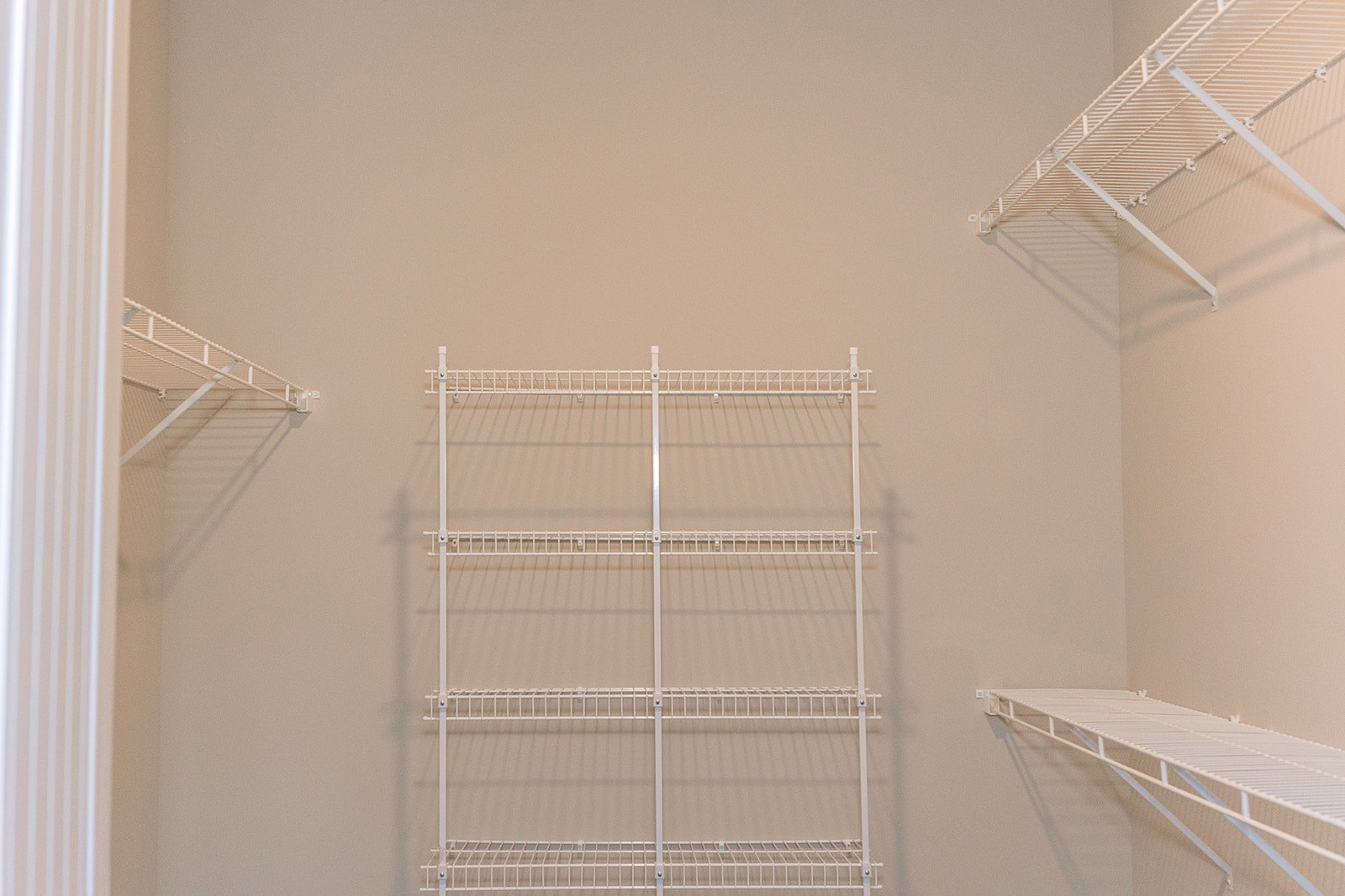 White built-in shelves mounted on a plaster wall near a staircase in a modern indoor space