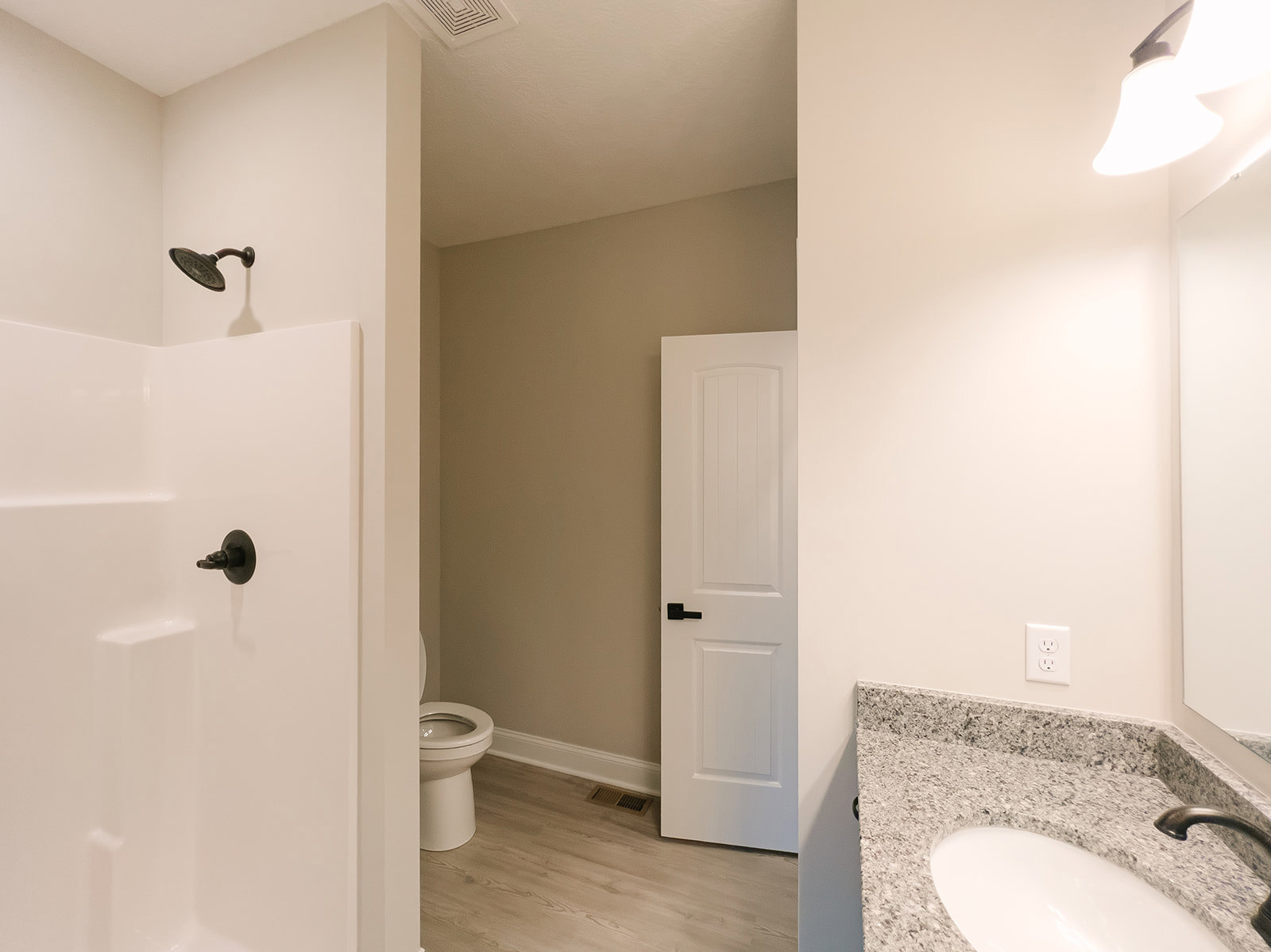 Modern bathroom with white toilet, rectangular sink, wall-mounted mirror, black faucet, and light gray tile walls