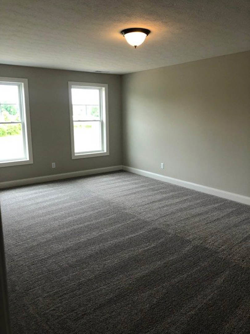 Carpeted room with white walls, ceiling light fixture, and a window with a white frame