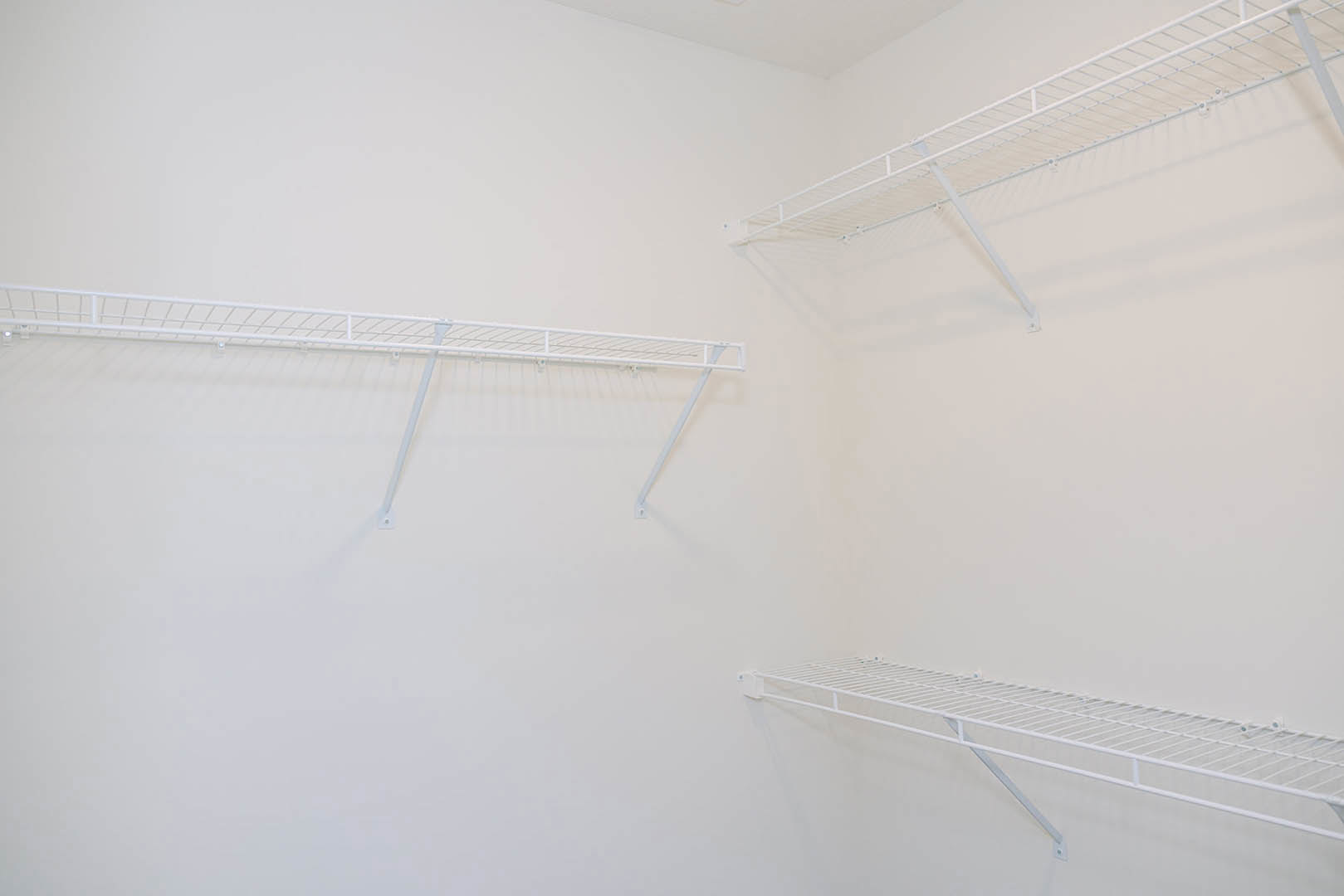 White metal shelf mounted on a smooth white plaster wall in a minimalist interior room