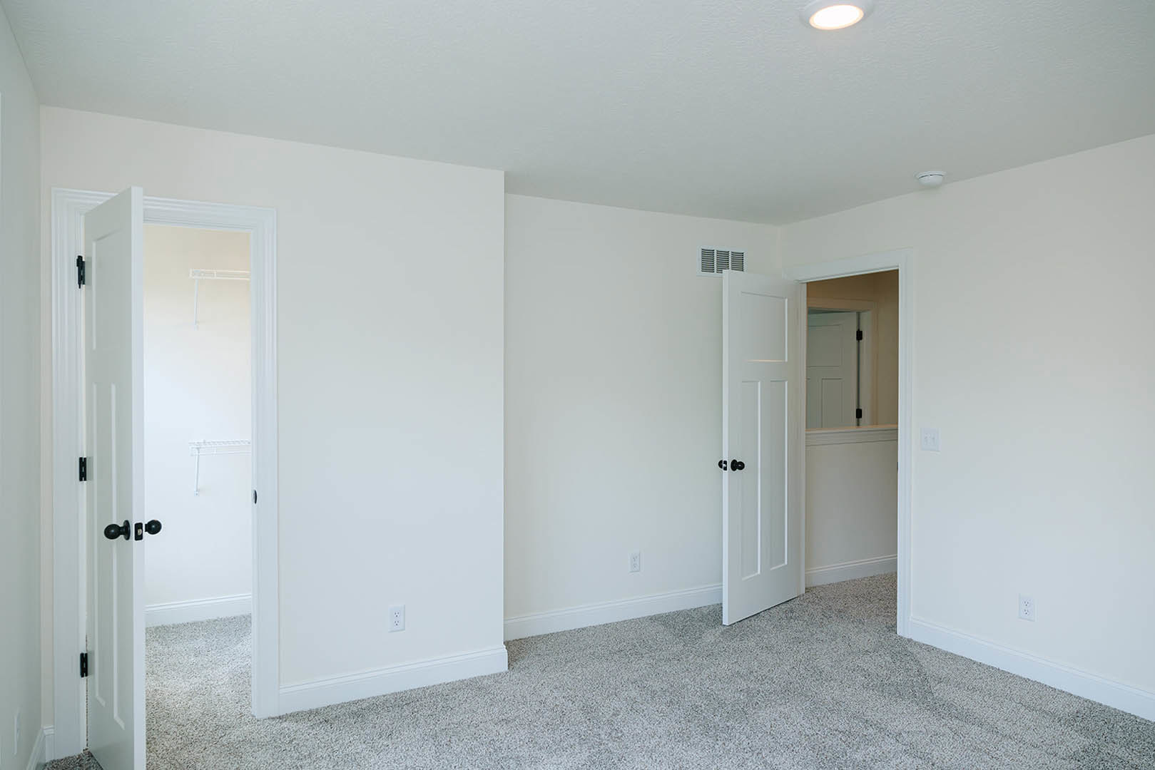 White door with black knobs open to a room featuring carpeted floor, white walls, and white door frame