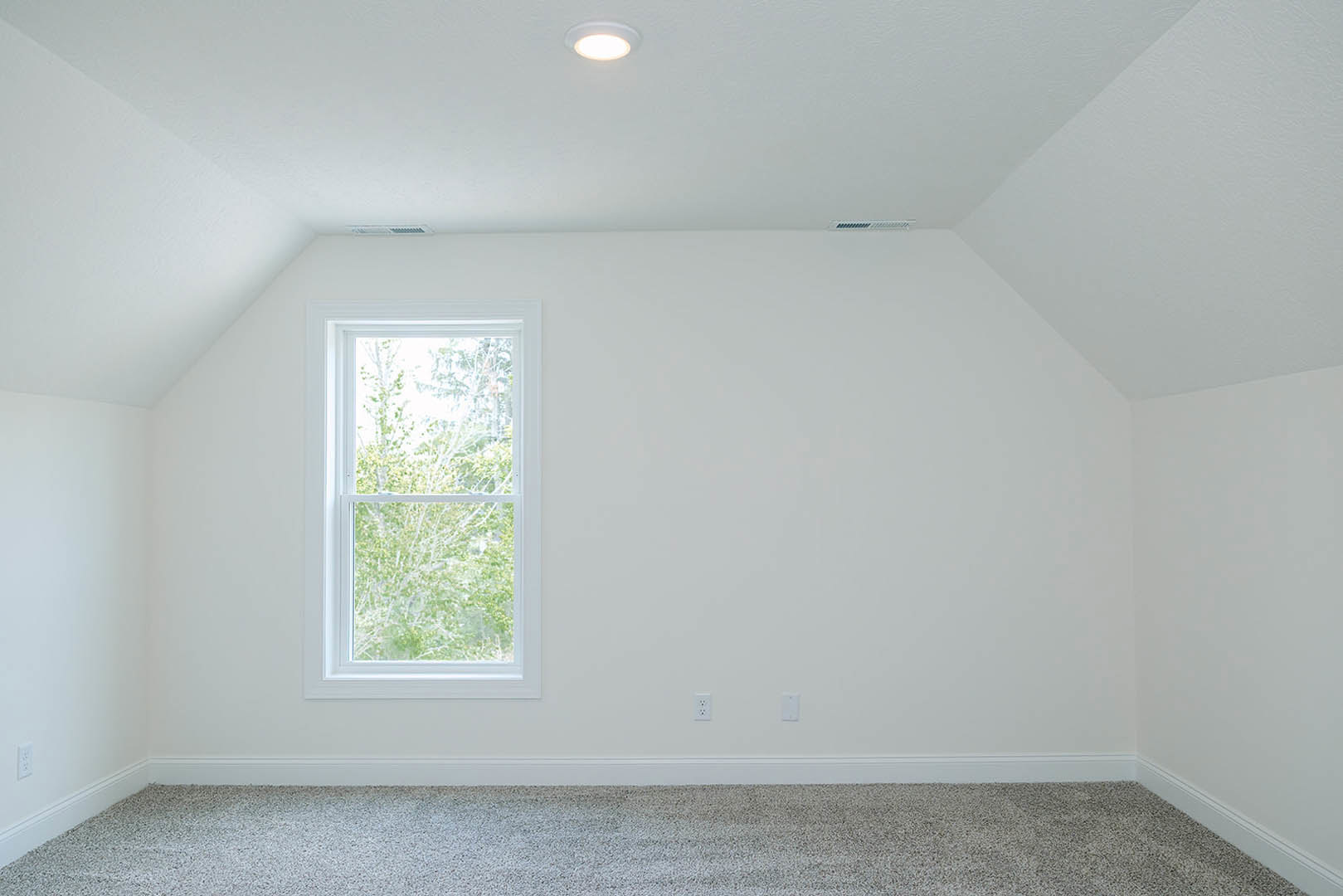 Carpeted room with white walls, large window overlooking trees, recessed ceiling light, and simple baseboard molding