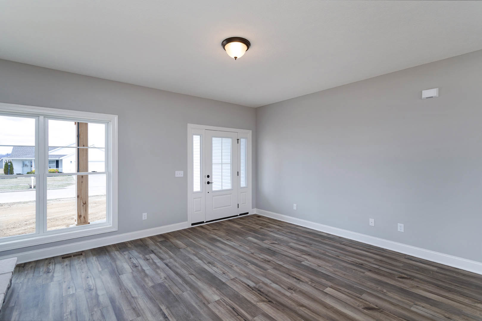 Wood flooring with white walls, white door featuring glass panels, ceiling light fixture, window overlooking neighboring house