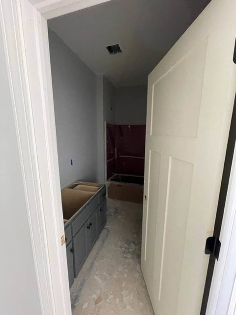 Hallway featuring white cabinetry, a white door with black trim, light flooring, and built-in shelving.