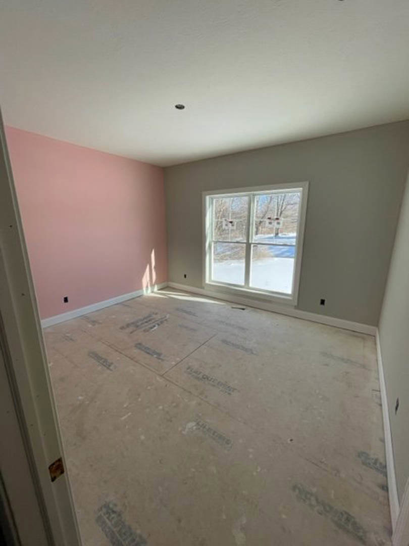 Pink-walled room with white trim, large window overlooking outdoor basketball hoop, light-colored flooring