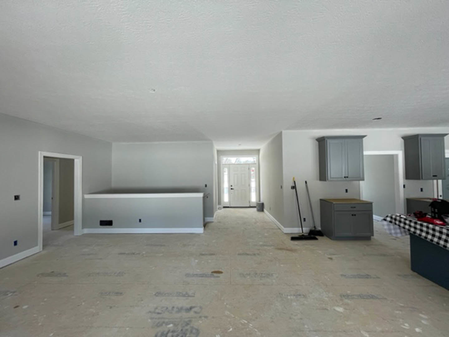 White painted wall with built-in gray cabinets, white door featuring a glass window, light-colored flooring, and smooth plaster ceiling.