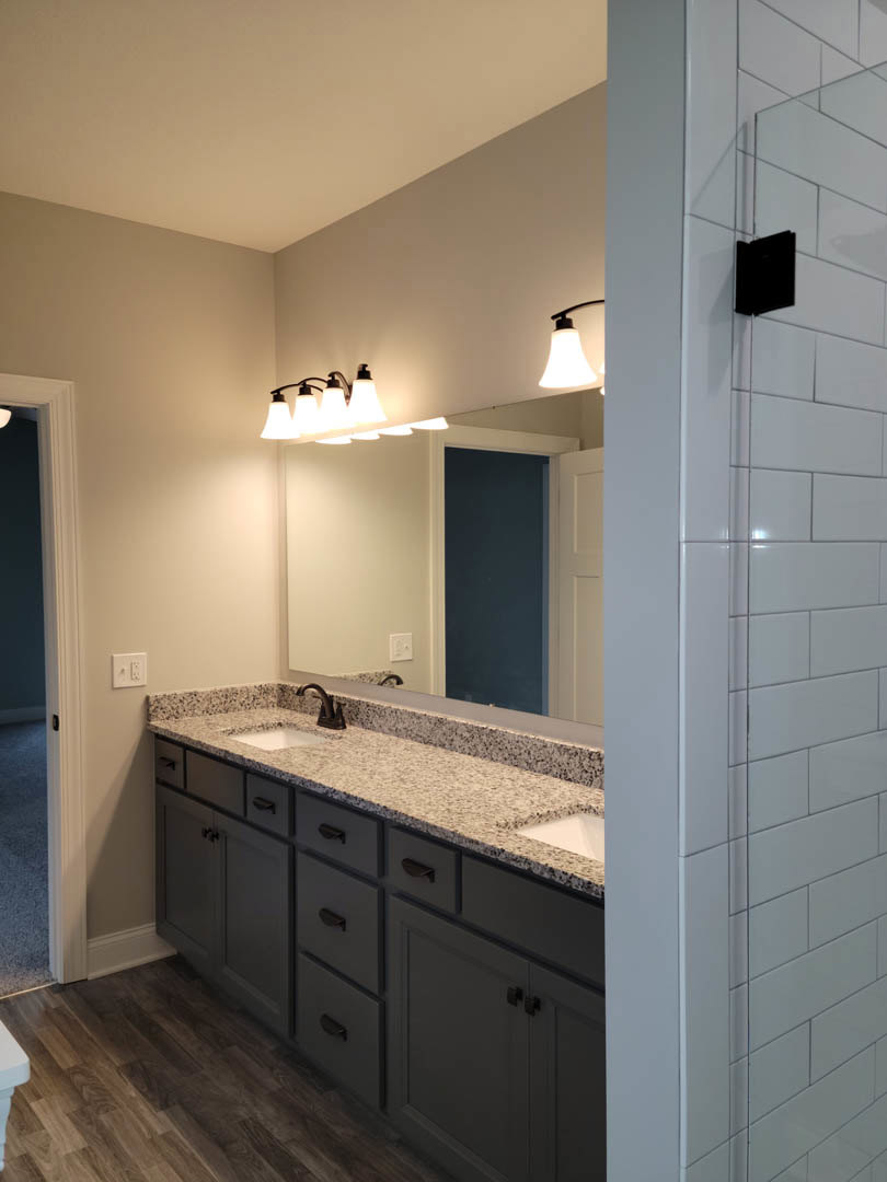 Bathroom featuring a marble countertop, large wall-mounted mirror, white tile backsplash, and modern black faucet.