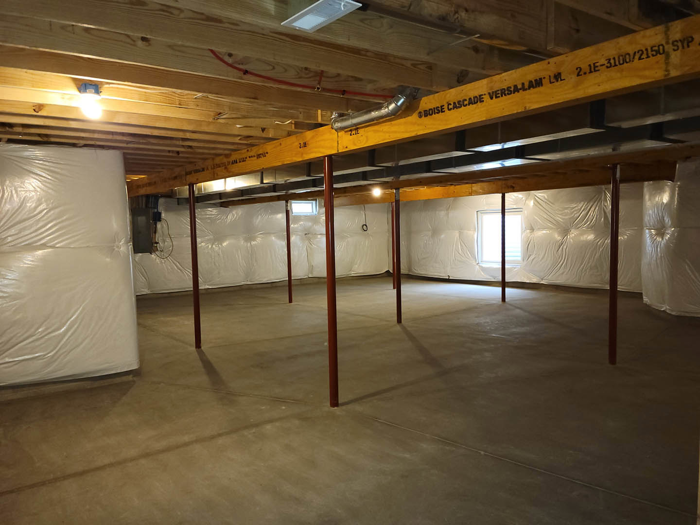Living room with exposed wooden ceiling beam, white couch, large white sheet covering the floor, neutral walls, and soft natural lighting.