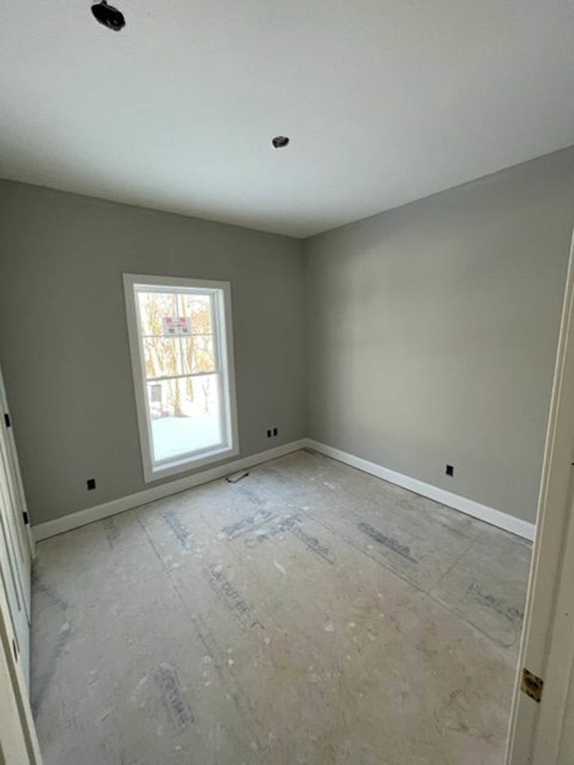 Room with large window, smooth concrete floor, white walls, and white door with matching trim