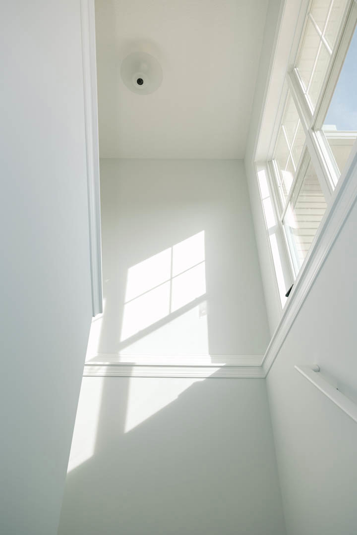 White plaster walls with black trim, large window, and modern ceiling light fixture in a bright interior room.