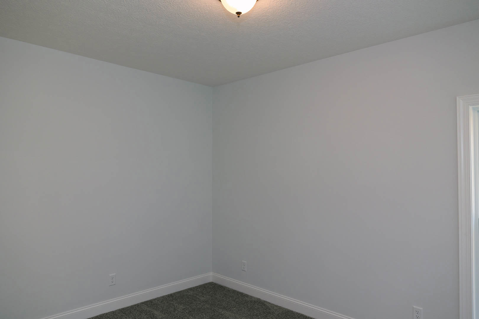 White ceiling with recessed light fixture, white walls, white paneled door, beige carpet flooring, and crown molding in a residential room