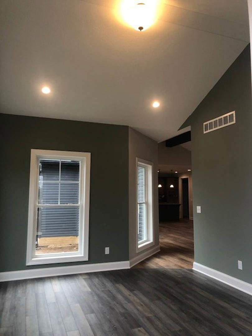 Sunlit room featuring a large window with white blinds, dark wood flooring, white baseboards, and smooth plaster walls.