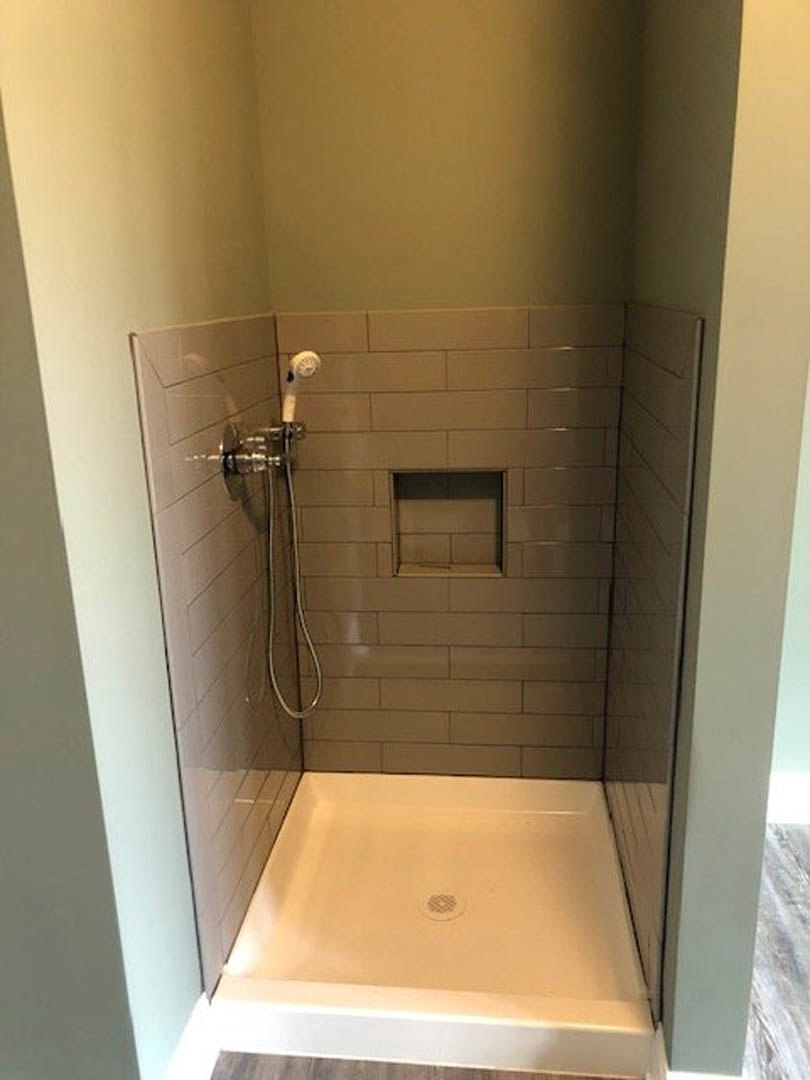 White tile shower with chrome shower head and floor drain