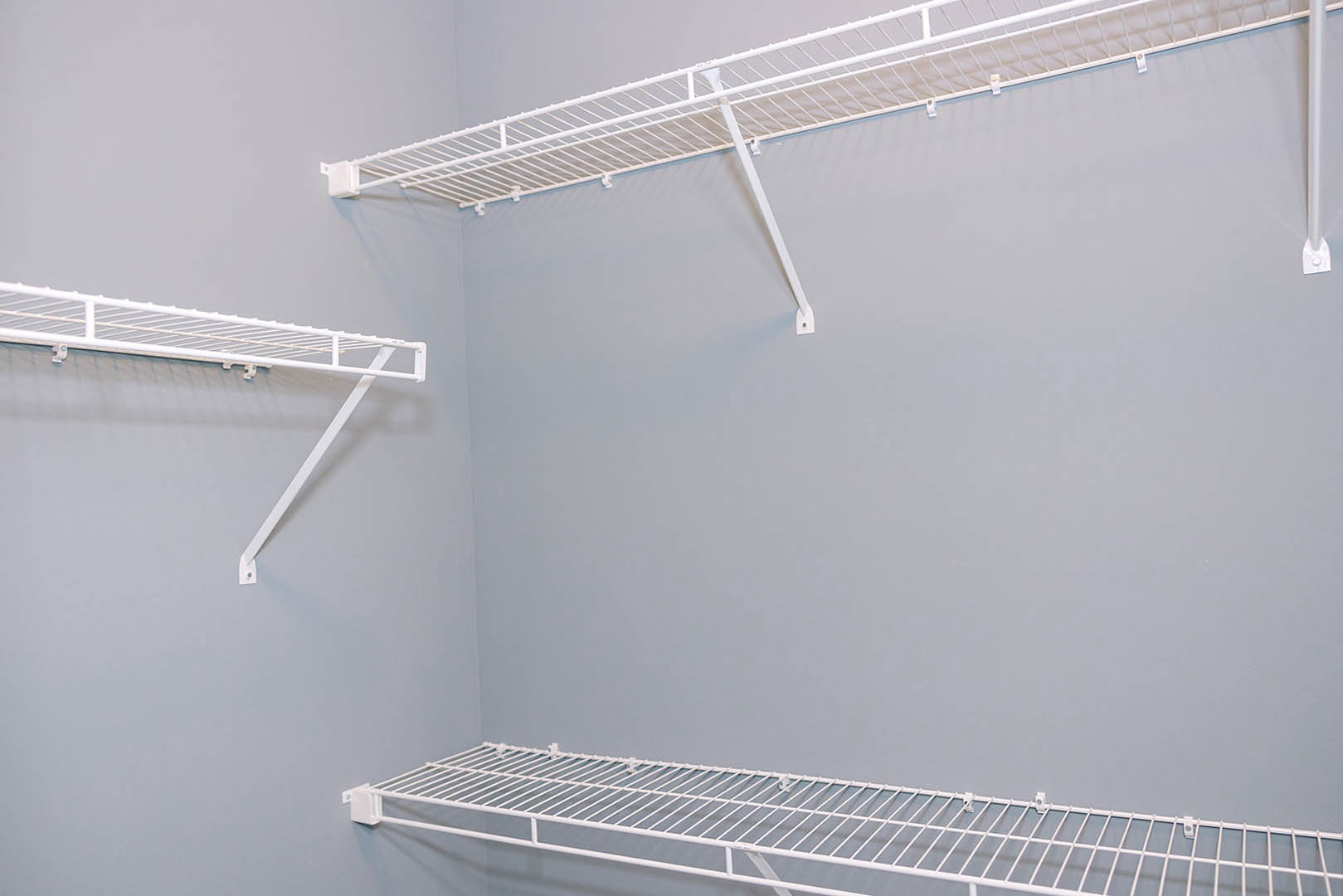 White built-in shelving unit against a smooth white wall with a slim metal rod and minimalist finishes.