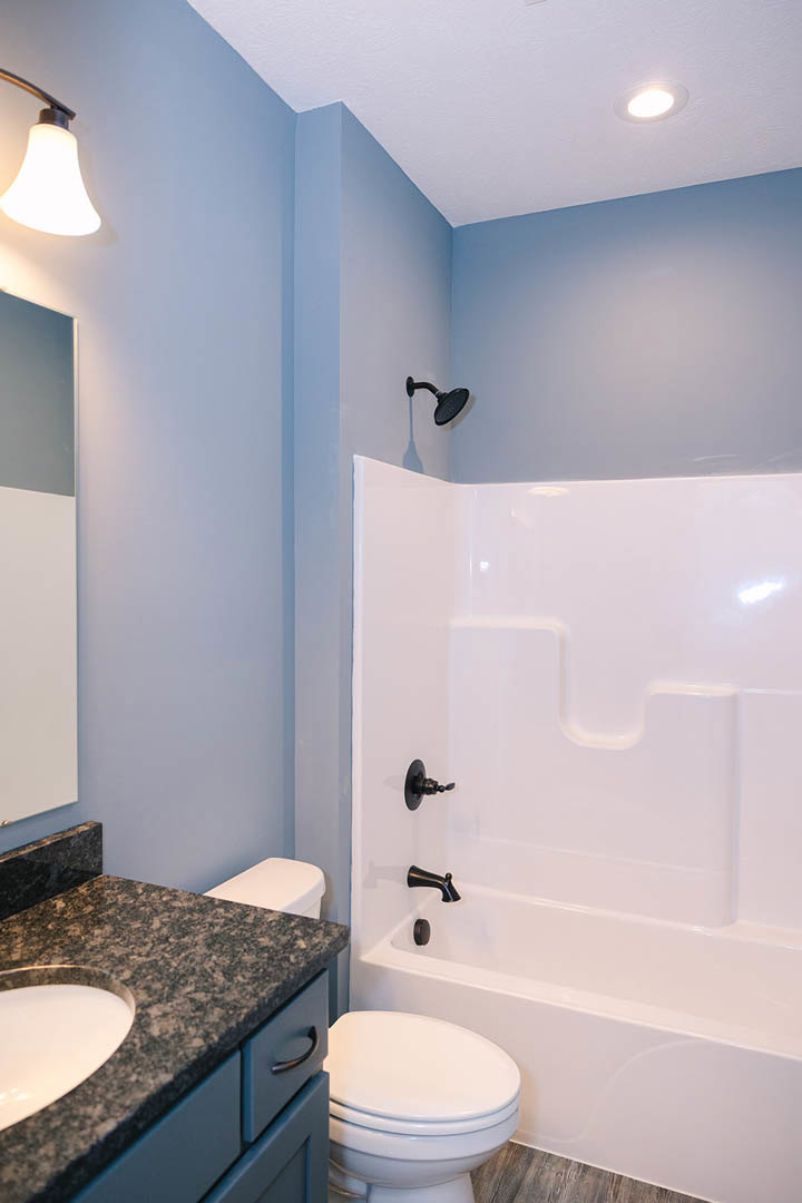 Modern bathroom featuring a freestanding white bathtub with matte black faucets, wall-mounted sink, tiled walls, and a glass-enclosed shower.