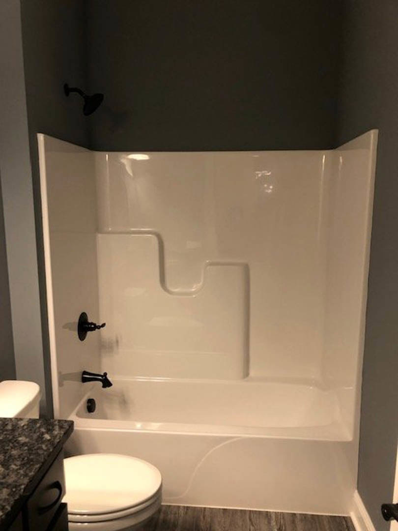 White freestanding bathtub and modern toilet set against light tile walls in a contemporary bathroom.