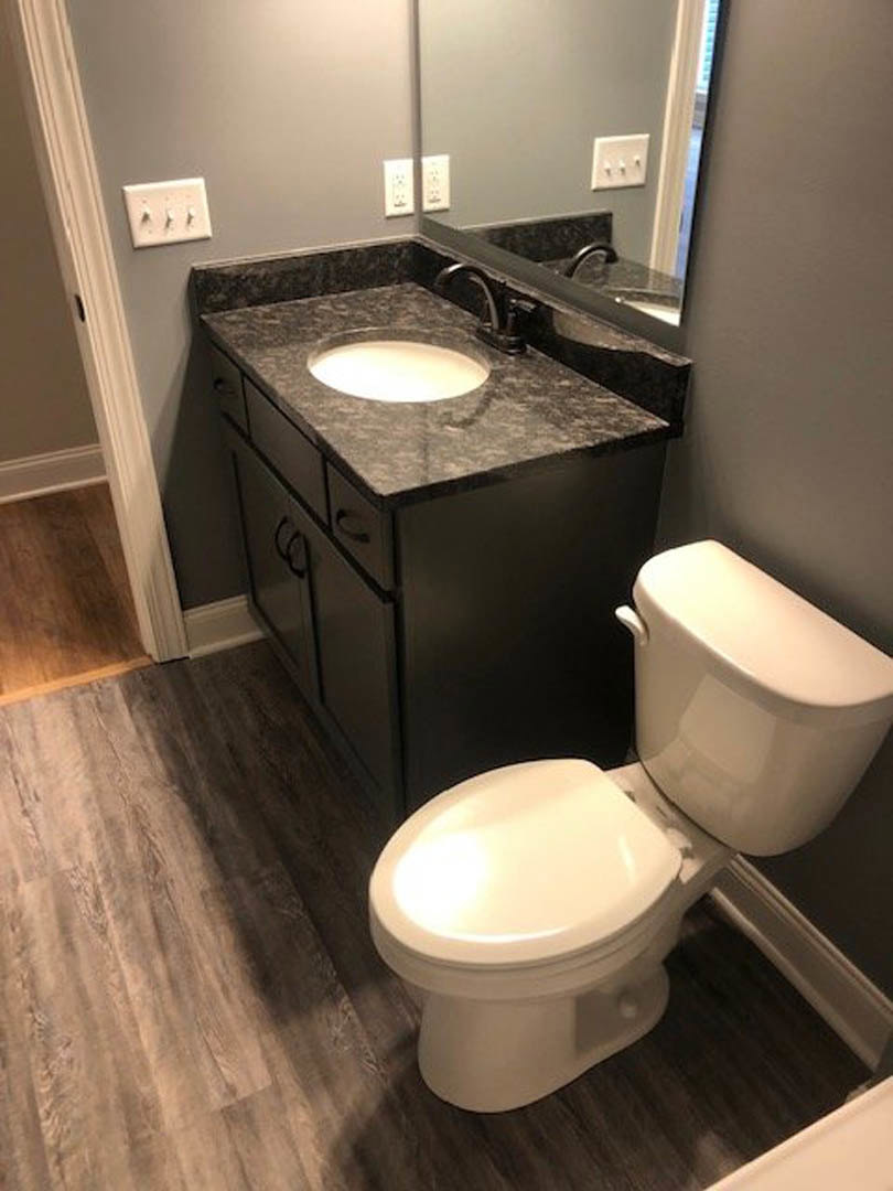 Marble countertop with undermount sink, white toilet, light gray tile floor, three-switch white light plate on wall